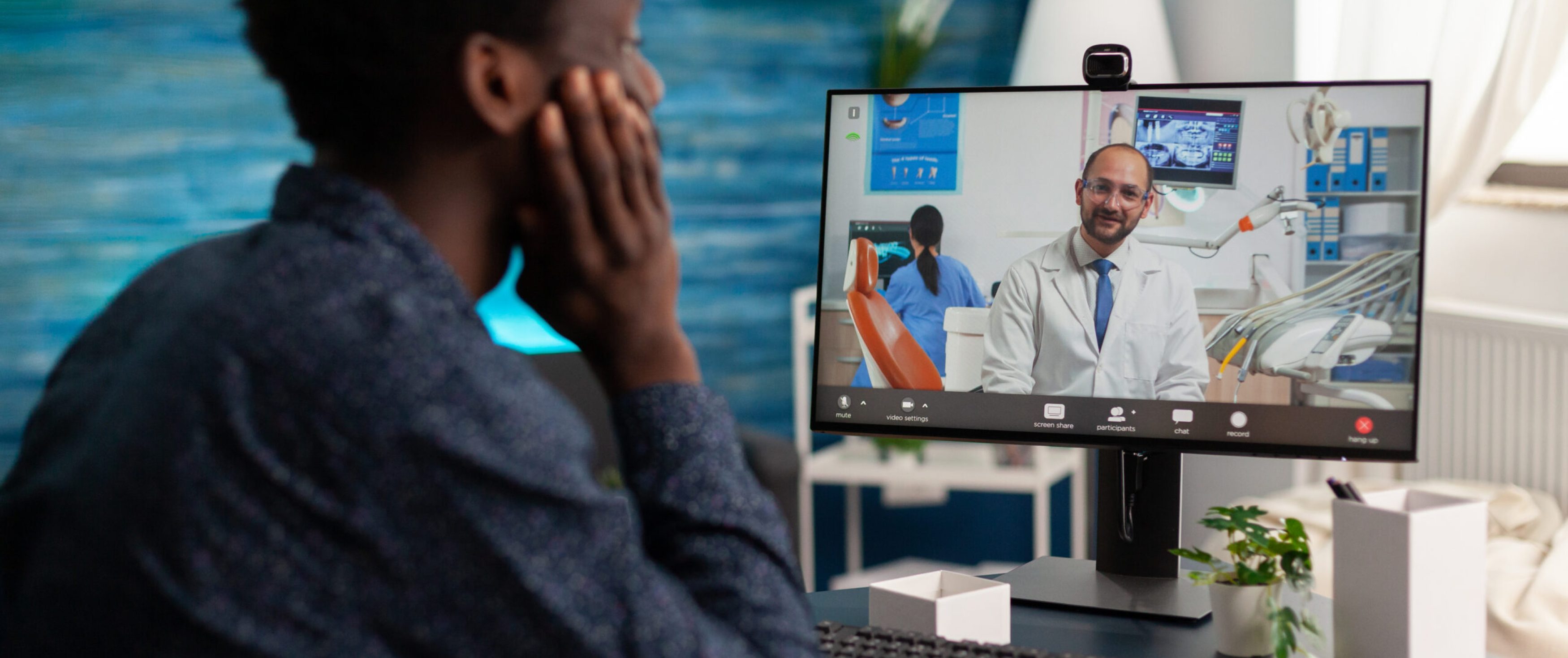 Black student with toothache pain discussing medical treatment with doctor during online videocall meeting conference. Man suffering painful illness. Telehealth videoconference call on computer